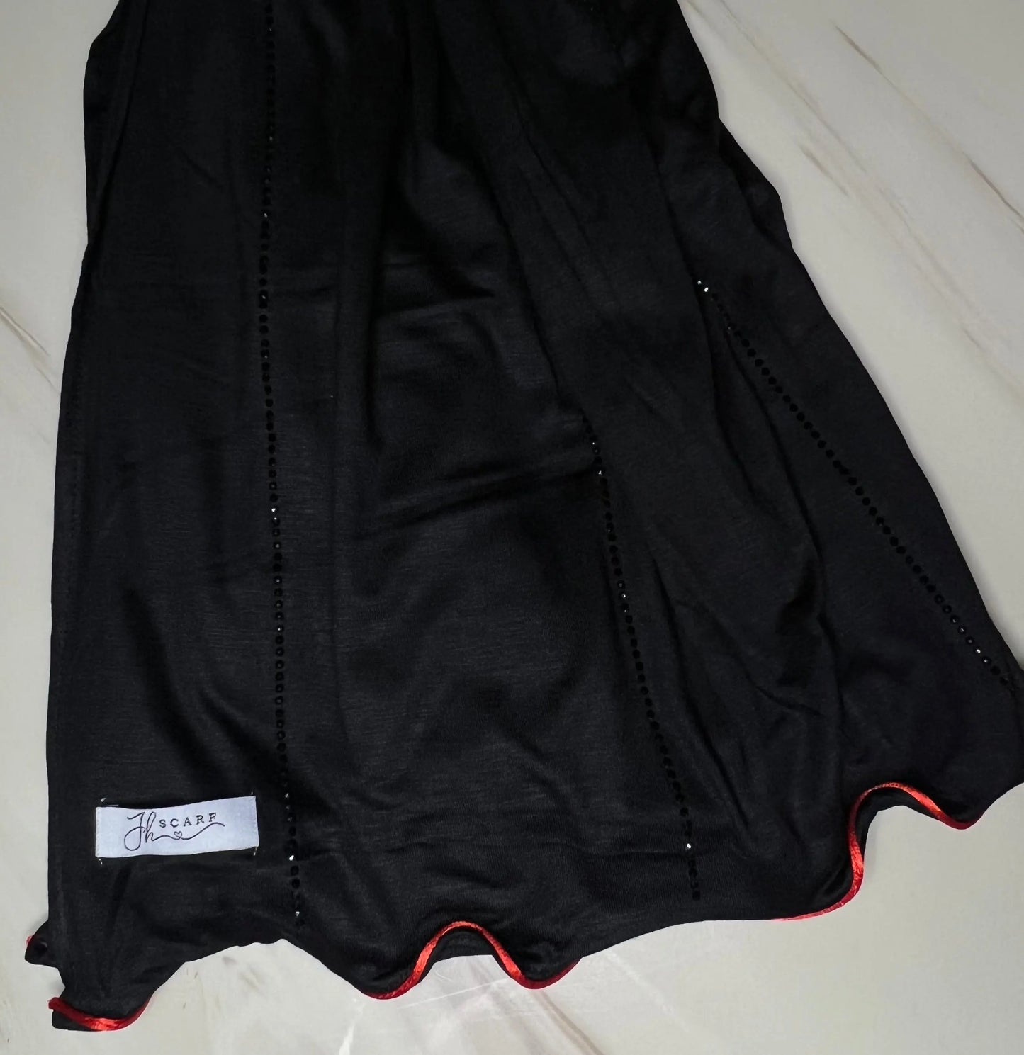 <img src="images/Jawahirnoirlrouge1.jpg" alt="Collection Hijab Jawahir
noir avec une ligne discrète rouge - Une gamme élégante de hijabs ornés de strass, importés de Dubai.">